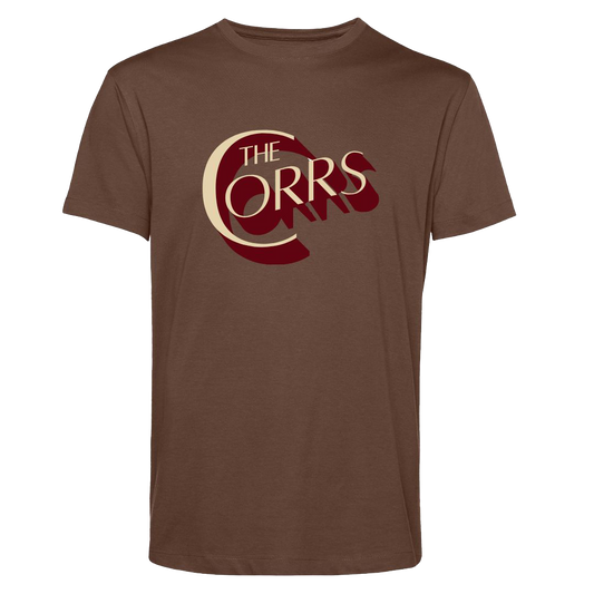 The Corrs Serif Brown T-Shirt from The Corrs Store by National Merchandise features large cream and maroon THE CORRS text on soft ring-spun combed fabric, shown against a bright green background.