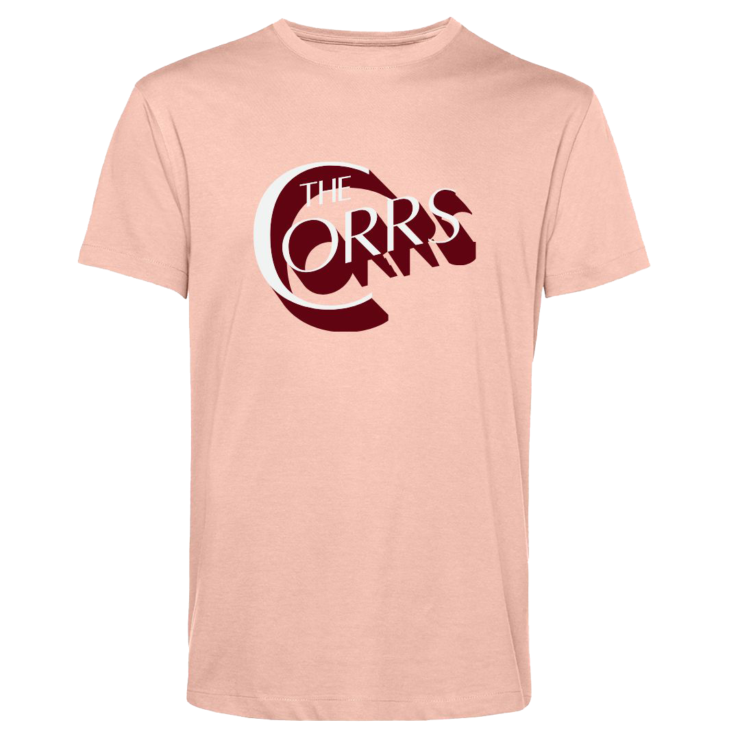 The Corrs Serif Soft Rose T-Shirt from The Corrs Store by National Merchandise is a light pink, organic tee with bold dark red and white The Corrs text on soft 145gsm fabric, shown on a bright green background.