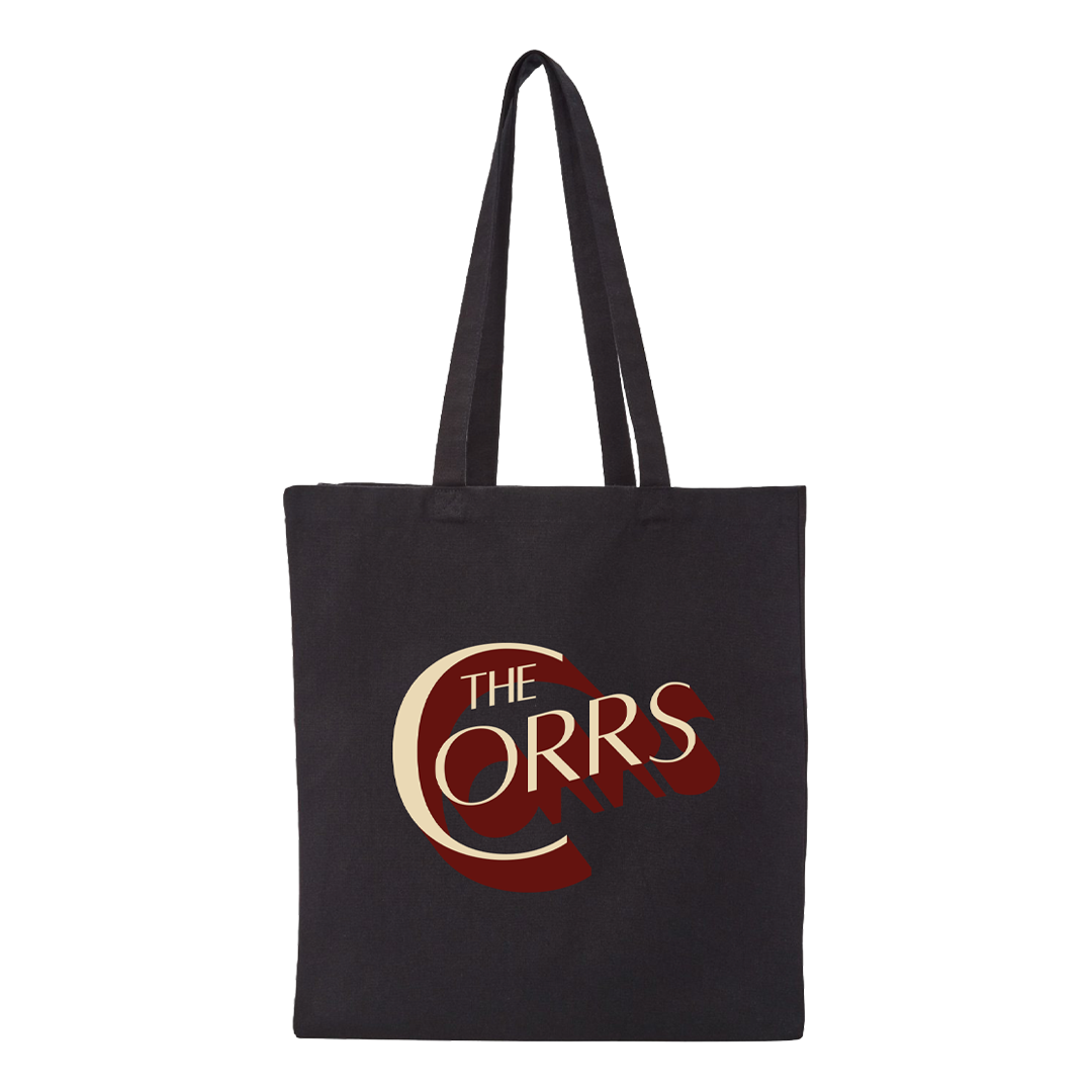 The Corrs Black Tote Bag from The Corrs Store by National Merchandise features a large stylized cream and dark red “C” with shadow detailing, along with The Corrs logo, printed and centered on the front.